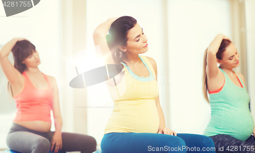 Image of happy pregnant women exercising on fitball in gym