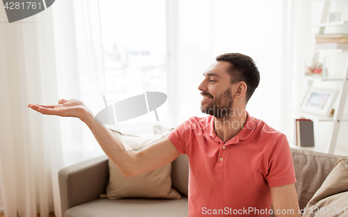 Image of happy man holding something imaginary at home