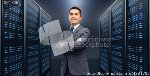 Image of smiling businessman over server room background