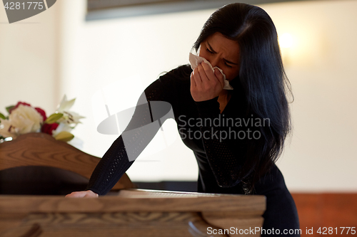 Image of woman with coffin crying at funeral in church