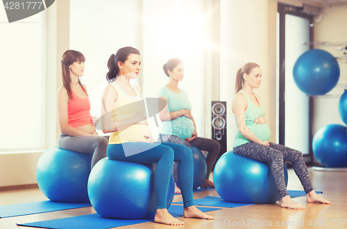 Image of happy pregnant women exercising on fitball in gym