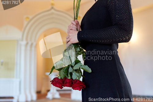 Image of woman with red roses at funeral in church