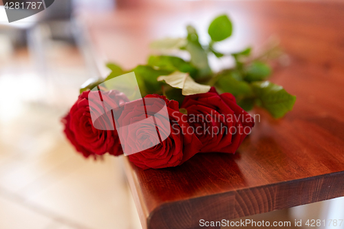 Image of red roses on bench at funeral in church