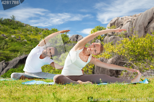 Image of happy couple making yoga exercises outdoors