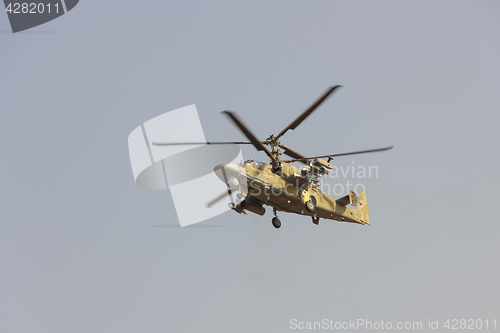 Image of Green helicopter flies against the blue sky