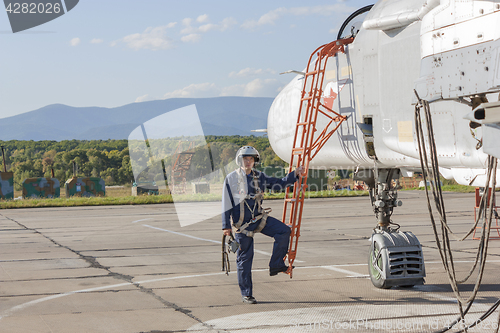 Image of Military pilot in helmet stands near jet plane