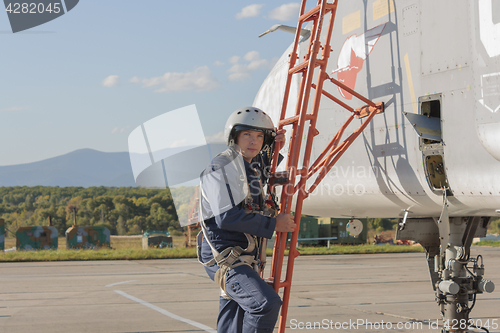 Image of Military pilot in helmet stands near jet plane