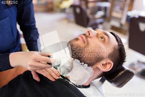 Image of man and barber applying shaving foam to beard