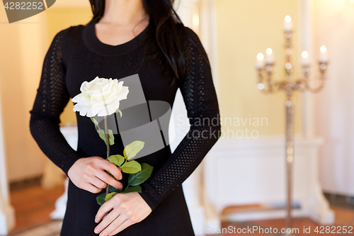 Image of woman with white rose at funeral in church
