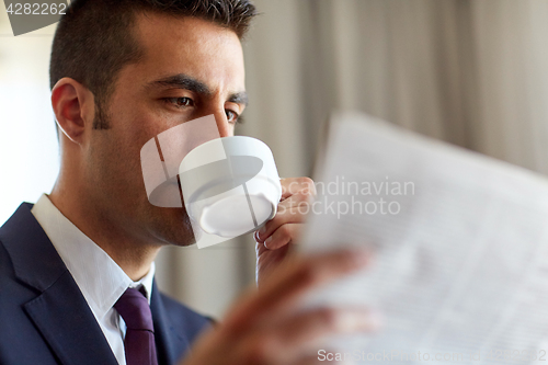 Image of businessman reading newspaper and drinking coffee