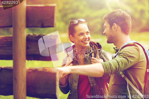 Image of smiling couple at signpost with backpacks hiking