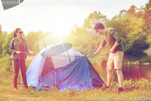 Image of happy couple setting up tent outdoors