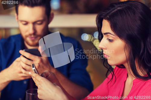 Image of couple with smartphones dining at restaurant