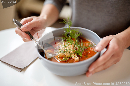 Image of woman eating seafood soup at restaurant