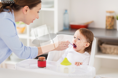 Image of happy mother feeding baby with puree at home