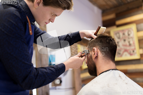 Image of man and barber with trimmer cutting hair at salon