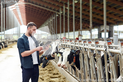 Image of young man with tablet pc and cows on dairy farm