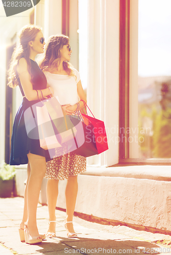 Image of happy women with shopping bags at shop window