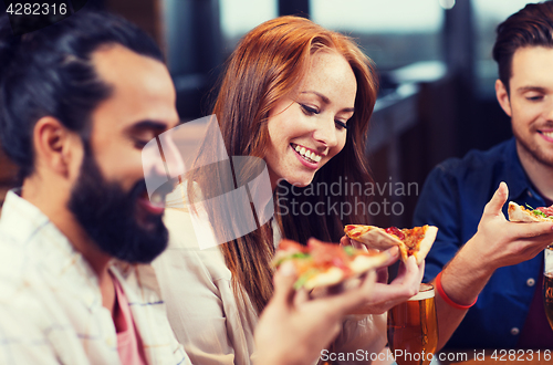 Image of friends eating pizza with beer at restaurant