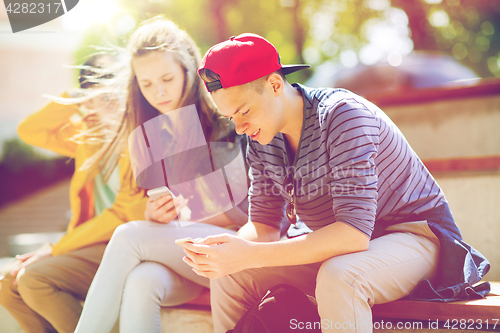 Image of happy teenage friends with smartphones outdoors