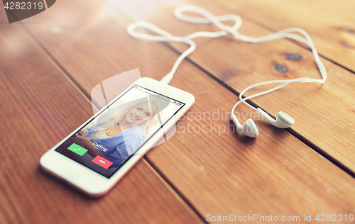 Image of close up of smartphone and earphones on wood