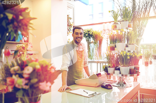 Image of florist man with clipboard at flower shop counter