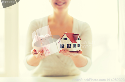 Image of close up of woman with house model and piggy bank