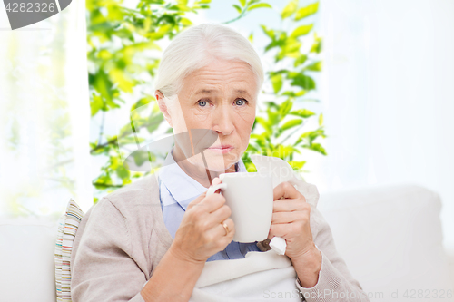 Image of sick senior woman drinking hot tea at home