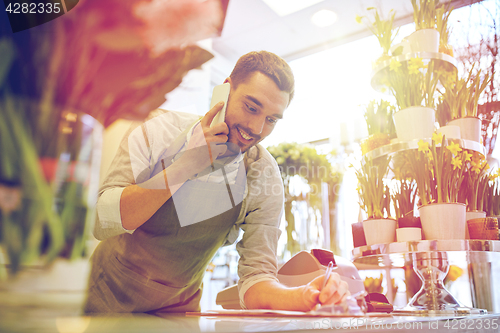 Image of man with smartphone making notes at flower shop