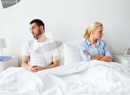 Image of unhappy couple having conflict in bed at home