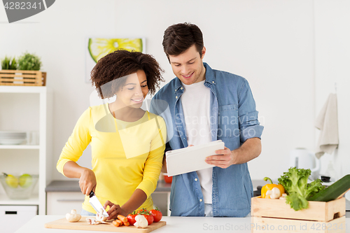 Image of happy couple with tablet pc cooking food at home