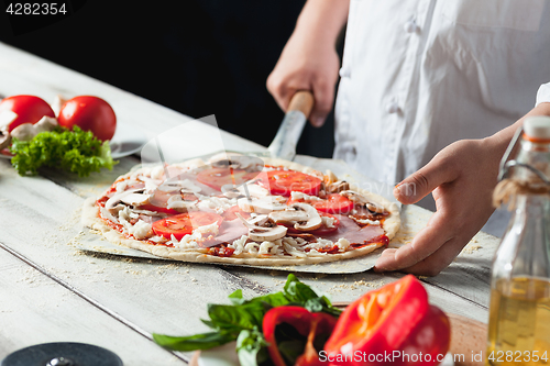 Image of Closeup hand of chef baker in white uniform making pizza at kitchen