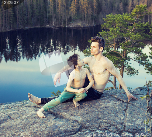 Image of middle age man with little cute son doing sport yoga on the top of the mountain together, happy family lifestyle people outdoor, summer wild nature for training close up