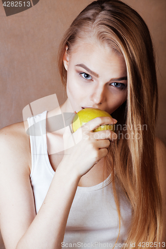 Image of young pretty blond woman with green apple happy cheerful smiling