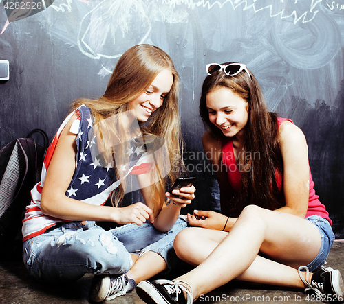 Image of back to school after summer vacations, two teen real girls in classroom with blackboard painted together, lifestyle people concept