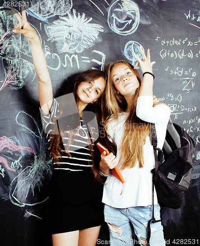 Image of back to school after summer vacations, two teen real girls in classroom with blackboard painted together, lifestyle people concept