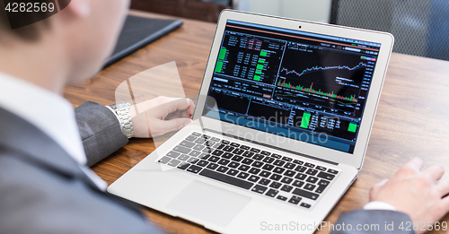 Image of Young businessman analyzing economic data on laptop computer.