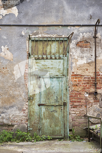 Image of grunge metal door, cracked brick wall