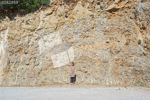 Image of Young woman standing near the mountain slope