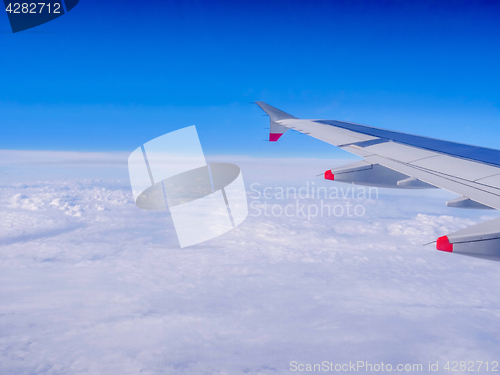 Image of View from a plane window: a plane wing over clouds and blue sky