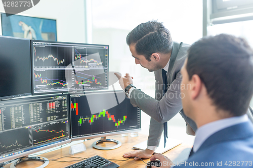 Image of Stock brokers looking at computer screens, trading online.