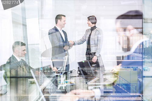 Image of Business people shaking hands in moder corporate office.