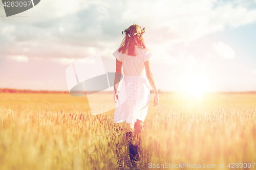 Image of happy young woman in flower wreath on cereal field