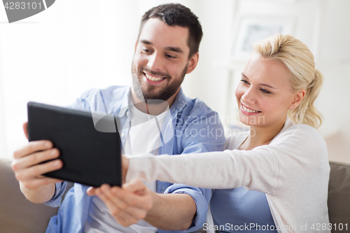 Image of smiling happy couple with tablet pc at home