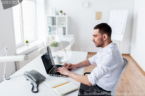 Image of businessman typing on laptop at office