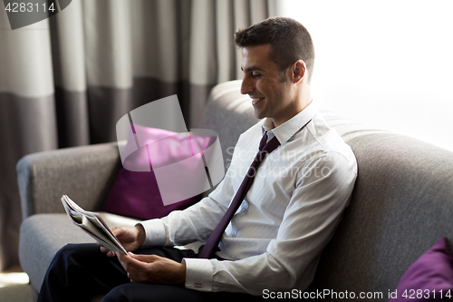 Image of happy businessman reading newspaper at hotel room