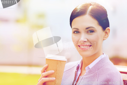 Image of smiling woman drinking coffee outdoors