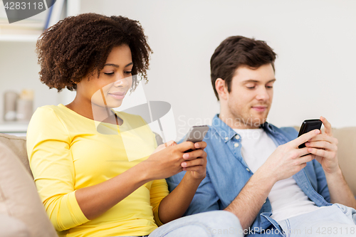 Image of happy couple with smartphones at home