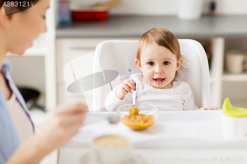 Image of happy mother and baby having breakfast at home