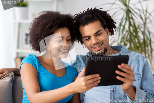 Image of smiling happy couple with tablet pc at home